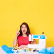 © sementsova321 - Photo of impressed attractive woman opening mouth and eyes widely, making gesture, pointing up with forefinger, sewing clothes, working at tailor studio, being shocked. Copyspace for advertisement.