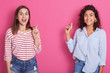 © sementsova321 - Image of smiling adorable beautiful brunettes making gestures, raising forefingers, showing direction, looking directly at camera, being in good mood. Copyspace for advertisement. Emotions concept.