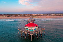 Aerial View Of Wooden Pier In Huntington Beach, Orange County In California At Sunset With Waves Crashing Below At Sunset, Indicative Of Travel Tourism And Vacation Time.