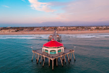 Aerial View Above The Huntington Beach Pier In Orange County, California On A Sunny Day With Ocean Water Below And People Walking On Pier.