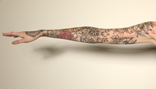 Woman With Colorful Tattoos On Arm Against White Background, Closeup
