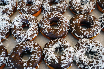 Wall Mural - Fresh donuts with chocolate icing and coconut flakes