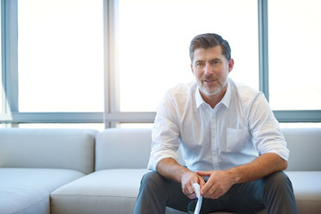 Wall Mural - Mature businessman on couch looking thoughtful with paperwork