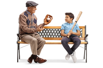 Elderly man with basbeball glove and ball talking to a boy and sitting on a bench