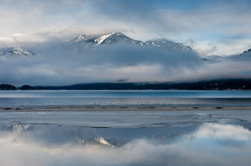 Wall Mural - Harrison Lake, British Columbia, Canada  in Winter. Low clouds envelope the surrounding mountain range with snow capped peaks seen in the background.