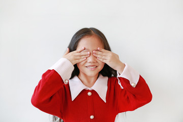 Wall Mural - Portrait of happy little Asian child girl covering eyes with hands isolated over white background.