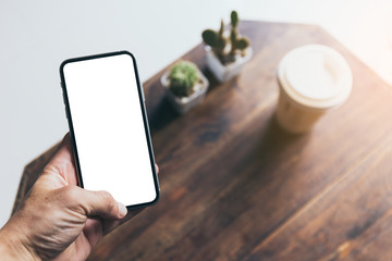 Mockup image blank white screen cell phone.man hand holding texting using mobile on desk at coffee shop.background empty space for advertise text.people contact marketing business,technology 