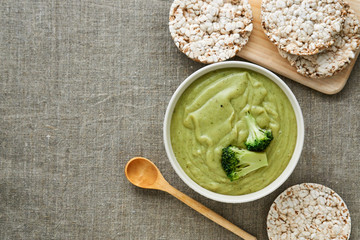 Wall Mural - Broccoli cream soup in a white bowl on a textile background 