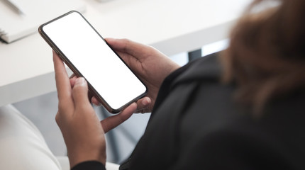 Cropped shot view of woman hands holding smart phone with blank copy space screen for your text message or information content, female reading text message on cell telephone during in urban setting. 