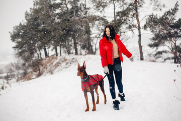 Wall Mural - Cute girl walking in a winter park. Woman in a red jacket. Lady with a dog