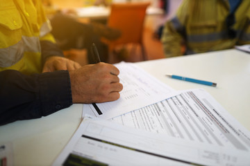 Wall Mural - working at heights permit book placing on the table, defocused construction site supervisor reviewin