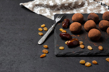 Wall Mural - Homemade vegan truffles with dried fruits, walnuts and raw cocoa powder on black slate plate