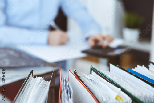 Fotografía Binders of papers waiting to process by bookkeeper woman or financial inspector, close-up