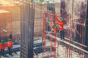 Workers are working on construction site, labourers wearing vest and safety helmet, construction crews on steel work at the building