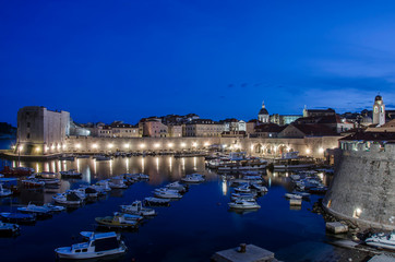 Wall Mural - View of Dubrovnik fortress walls at night, Dubrovnik, Croatia. Fortress walls, rocky coast, blue sea and small yachts and boats.