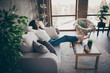 © deagreez - Profille side view portrait of her she nice attractive charming cheerful cheery glad wavy-haired girl sitting on divan resting spending day at modern industrial loft interior style living-room indoors
