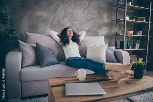 Low angle view portrait of her she nice attractive slim fit thin slender cheerful cheery dreamy wavy-haired girl sitting on divan resting at modern industrial loft interior style living-room indoors