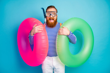 Surprised amazed redhair beard man hold float saver scream want rescue rest people breathing tube mask wear goggles white stylish trendy style striped shirt shorts isolated blue color background