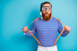 Portrait of astonished redhair man train watersport swim coral reef pull his modern suspenders wear protective mask tube white shorts nautical vest isolated over blue color background