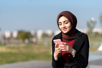 Wall Mural - muslim young woman typing message with her smartphone