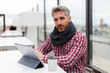 © Ignacio Ferrándiz - Young man sitting on a terrace in front of an electronic tablet and a reusable glass facing the camera