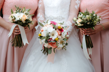 Wall Mural - bride in white wedding dress holds beautiful wedding bouquet with girlfriends in pink dresses