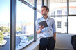 © marvent - Young businessman looking out window while holding digital tablet