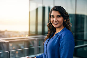 smiing young businesswoman standing on an office balcony at dusk