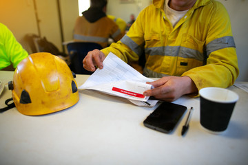 Wall Mural - planner site engineer sitting placing safety hard hat on the table coffee cup pen reviewing jsa risk