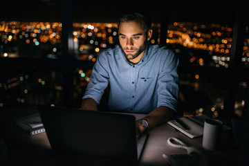 Young businessman working late at night on a laptop