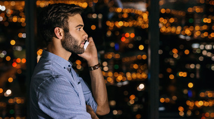 Wall Mural - Businessman working late at night talking on a cellphone