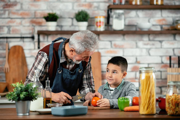 Wall Mural - Grandpa and grandson in kitchen. Grandfather and his grandchild having fun while cooking.