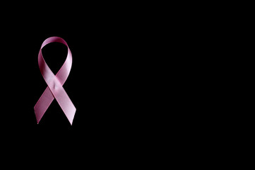 pink ribbon, a symbol of breast cancer awareness, isolated on a black background. space for text