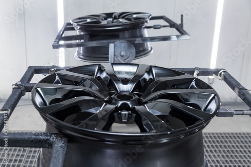Cuadros en Lienzo A Two black painted aluminum alloy wheel is mounted on a special frame during drying in a chamber in a vehicle body repair workshop