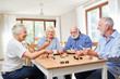 Leinwandbild Motiv Senioren als Freunde spielen zusammen Domino