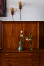 Vertical Image Of Two Simple Vases With Poppies And Daffodil On A Wooden Bureau