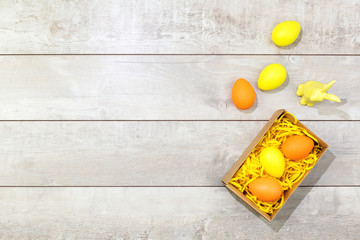 Wall Mural - Several bright color dyed easter eggs with a rabbit on wooden background in flat lay with copy space. Border for Happy Easter minimal concept card or banner