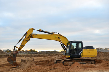 Canvas Print - Excavator digs the ground for the foundation and construction of a new building. Road repair, asphalt replacement, renovating a section of a highway, laying or replacement of underground sewer pipes