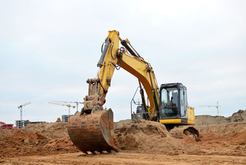 Canvas Print - Excavator digs the ground for the foundation and construction of a new building. Road repair, asphalt replacement, renovating a section of a highway, laying or replacement of underground sewer pipes