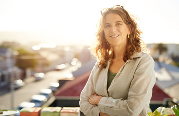 Wall Mural - Smiling mature woman standing on her apartment patio