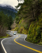 Green Sedan Driving On Curvy Mountain Hwy, Foggy Mountain, Green. Hills And Trees