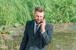 © Алексей Горелов - a man in a business suit in a swamp talking on the phone. business and office work concept