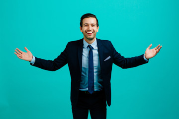 Portrait of a young entrepreneur business man smiling with arms open,  isolated on blue studio background