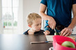 © Cavan Images - father making his kids packed lunches for school whilst son watches