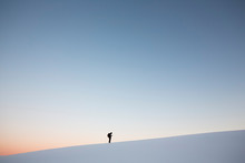 Man Standing On Snowcapped Mountain Against Clear Sky At Sunset