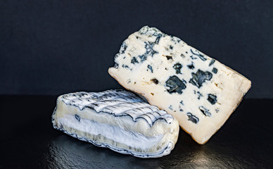 two pieces of cheese with mold on a black background close-up