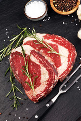 Wall Mural - Raw fresh meat Ribeye Steak, seasoning and meat fork on rustic background