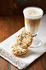 Almond cookies and cafe latte on brown wooden background.