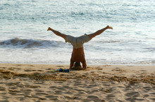 A Body Surfer Warms Up With A Handstand On The Beach Before Jumping Into The Hawaiian Pacific Ocean Water.