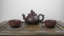 Ancient Teapot And Two Clay Bowls On A Wooden Surface With A White Background